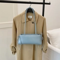 Minimalist light blue patent leather underarm bag with bow tie detail on a trench coat - Blue