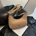 Bolso hobo creciente caqui con lazo plateado elegante sobre fondo de cuero oscuro - Caqui