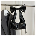 Detail of black patent leather bow bag featuring silver rivets and glossy finish - Black