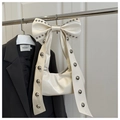 Detail of a creamy white bow handbag featuring silver metal rivets on glossy PU leather - White