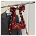 Detail of dark red underarm bag featuring oversized bow and metallic silver rivets - Red