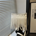Borsa a secchiello bianca con frange e borchie argentate in un ambiente interno moderno - Bianco