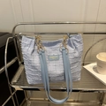 Bolso tote de cuadros azul claro con cadena dorada en un estante de exhibición - Azul
