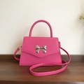 Elegant rose red bow handle bag with trapezoidal shape and silver buckle on wood desk - Rose Red
