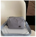 Detailed close-up of grey nylon crossbody bag with textured fabric and wide shoulder strap - Gray