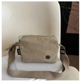 Close-up of khaki nylon shoulder bag featuring textured fabric and brand logo detail - Khaki