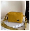 Detail of yellow nylon crossbody bag with canvas strap and metal logo on books - Yellow