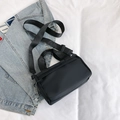 Minimalist black nylon crossbody pillow bag with adjustable straps on denim jacket - Black