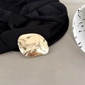 Vista macro de la pieza metálica irregular dorada pulida con marca sobre un tejido negro - Happy Geométrico Oro Brillante