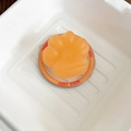 Gros plan du support de téléphone patte de chat orange avec gravure Good Luck sur la base - Patte de Chat Mate - Orange