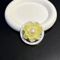 Détail macro d'un support de téléphone fleur nacrée avec perle sur socle décoré - Jaune