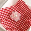 Detalle de soporte para móvil de flor rosa 3D con perla sobre fondo de cuadros - Rosa Blanco