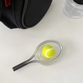 Detalle de mini raqueta de tenis plateada y pelota amarilla colgada en bolso negro - Grip Transparente Raqueta de Tenis Plata