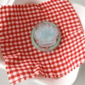 Macro shot of 3D cat paw phone stand with mint green Good Luck ring on checkered cloth - Green