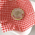 Close-up of translucent cat paw phone stand with heart relief on red plaid fabric - Jasmine Green