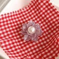 Detail of lavender metal flower phone socket with a glossy pearl center on checkered fabric - Gray