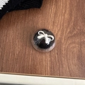 Detailed view of a round clear eyelash storage box with a silver bow ornament - Transparent Stand-Mink Fur Bow-Black