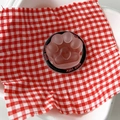 Close-up of pink cat paw phone grip with heart detail on red checkered background - Brown