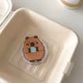 Close-up of cute acrylic capybara phone socket holder inside a minimal beige gift box - Magnetic Versatile Capybara No.1 (Holding Blue Object)