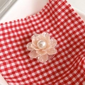 Close-up of pearl flower phone grip with pink translucent petals on checkered background - Light Orange