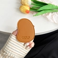 Close-up of brown leather phone socket with stitched edges and embossed letters - Golden Brown