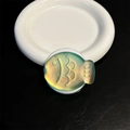 Macro detail of fish-shaped magnetic phone grip with yellow-green laser gradient finish - Magnetic / Dazzling Green
