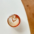 Detail view of a round 3D coffee latte art phone socket grip on a minimalist desk surface - Transparent Stand Crystal Glass Heart Latte Art