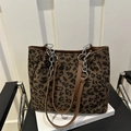 Borsa tote leopardata retrò con spallacci in pelle e dettagli catena su una sedia - Marrone