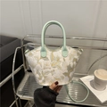 Minzgrüne Bucket Bag mit Blumenstickerei und Ledergriffen in legerer Innenaufnahme - Grün