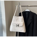 Close-up of off-white ruched tote bag featuring a silver metal butterfly buckle on pocket - With Pendant / White