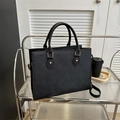 Classic black Saffiano leather business tote bag with gold hardware on display stand - Black