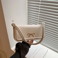 Elegant cream baguette shoulder bag featuring a gold bow clasp and stylish knotted strap - White