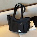 Borsa tote in tela nera con tasche laterali e spilla Good Luck su poltrona - Nero