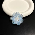 Gros plan d'un support de téléphone en forme de fleur bleue irisée sur une assiette - Support Transparent-Fleur Coquillage-Bleu Arc-en-ciel