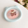 Detail view of brown resin bear phone back clip on a pastel blue bear-shaped tray. - Crystal Bowknot Bear - Brown