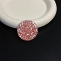 Macro shot of circular pink glitter resin phone grip on white ceramic and black leather - Red Round