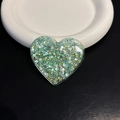 Detail of heart-shaped glitter phone socket with green and silver sequins on a white plate - Green Heart