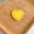 Detailed close-up view of a matte yellow heart-shaped phone ring holder stand on wood - Yellow