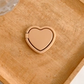 Close-up of a minimalist beige heart-shaped phone ring stand on a wooden background - Brown