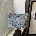 Blue denim checkerboard baguette bag with fringe edges and chain strap shown in hand - Checkered Blue