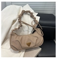 Macro detail of khaki pleated hobo bag fabric with a golden triangular logo - Khaki