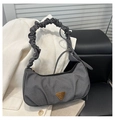 Close-up of grey textured handbag featuring scrunchie handle and gold triangle plaque - Black
