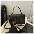 Detailed close-up of black quilted texture with elegant gold hardware lock on bag - Black