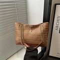 Lazy style straw woven tote bag with chain strap and deer charm shown in a warm setting - Brown