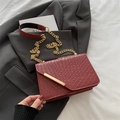 Burgundy woven texture flap bag with gold chain strap shown on grey blazer background - Red