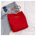 Detail of red canvas tote bag featuring colorful woven rope handles and checkered lining - Red