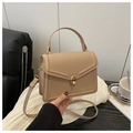Detail der beigen Handtasche mit goldenem Drehverschluss auf Ledersofa Hintergrund - Khaki