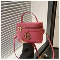 Detail der pinken Box-Tasche mit goldenem M-Logo, Doppelreißverschluss und Tragegriff - Rosenrosa