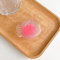 Close-up of pink translucent fish-shaped silicone phone grip on a wooden tray - Rose Red
