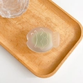 Close-up of frosted fish-shaped phone grip with relief texture on a wooden tray - Moss Green